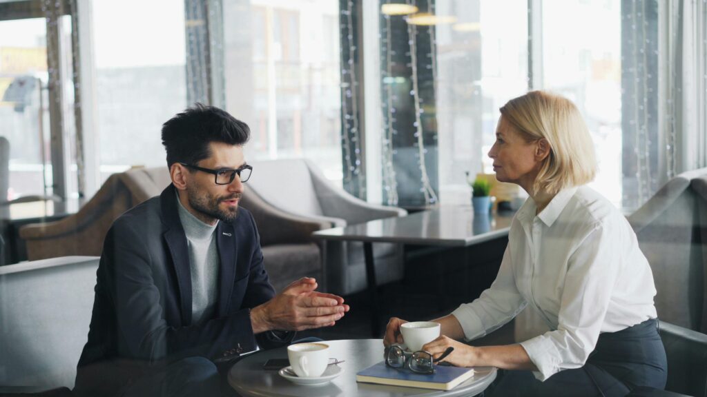 Businessman and businesswoman having a discussion over coffee in a stylish cafe setting.